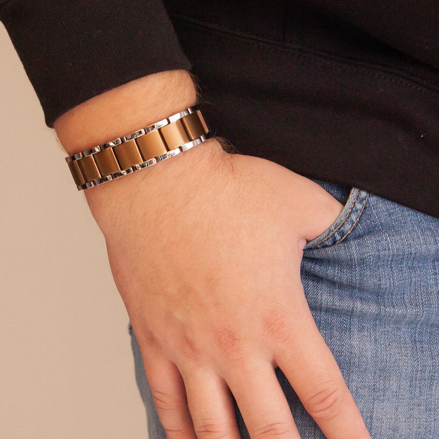 Close-up of bracelet on wrist, worn by model with thumb in pocket, highlighting bracelet design and links.