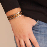 Close-up of bracelet on wrist, worn by model with thumb in pocket, highlighting bracelet design and links.