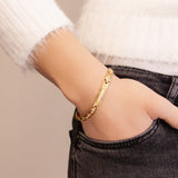 Woman wearing the Adored gold stainless steel bracelet with hand in pocket, showing sparkling crystal center link and polished finish.