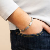 Male model wearing Alluring bracelet with matte stainless steel links and polished gold spacers, hand in pocket.
