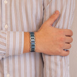 Male model with Blue Moon bracelet resting hand on opposite arm, highlighting bold matte and polished titanium link design.