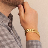 Male model wearing the Dual Tone gold-plated titanium bracelet, hand resting on chin to display dual finishes and elegant link design.