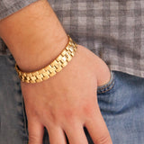 Man wearing the Dual Tone gold-plated titanium bracelet with thumb in pocket, showing links with matte and polished gold contrast.