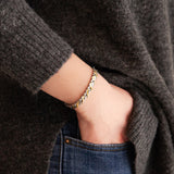 Duet gold and stainless steel bracelet on wrist, hand in pocket showing fluid wave-link design and soft dual-tone shine.
