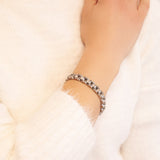 Close-up of female model with Elegant Flower bracelet on wrist, showing the subtle reflection of its polished silver-toned links.