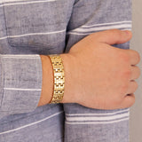 Male model wearing the Golden Bliss polished gold stainless steel bracelet, hand resting on opposite arm to display angular links and polished gold finish.