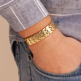 Man wearing the Golden Bliss polished gold stainless steel bracelet with hand in pocket, showing engraved checkered links and reflective gold finish.