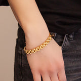 Female model wearing the Golden Breath bracelet, displaying polished gold-plated stainless steel with softly contrasting center links.