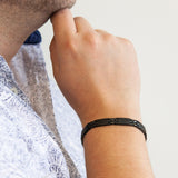 Male model wearing Millennial bracelet with matte and polished black links, hand resting on chin.