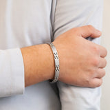 Male model wearing Reflection bracelet showing interlocking matte and polished links with hand resting on opposite arm.