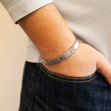 Male model wearing Reflection bracelet with matte stainless steel links and polished spacers, hand in pocket.