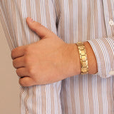 Male model wearing the Royal matte gold stainless steel bracelet, hand resting on opposite arm to display matte gold finish and polished edge contrast.
