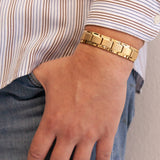 Man wearing the Royal matte gold stainless steel bracelet with thumb in pocket, showing polished borders and angular link design.