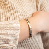 Close-up of SandStorm bracelet on wrist showing dual-tone stainless steel and gold finish.