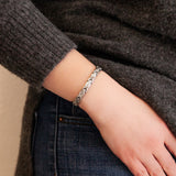 Female model wearing Serenity bracelet with polished X-shaped links and matte almond-shaped spacers.