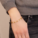 Woman wearing the Sparkle gold titanium bracelet with hand in pocket, showing shimmering crystals and polished gold links.