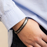 Male model wearing Swell bracelet with stainless steel links and polished black edges, thumb in pocket.