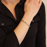 Female model wearing the Vibrant Spark titanium bracelet, hand resting on opposite shoulder to display elegant crystal detail and graceful titanium design.