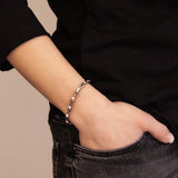 Woman wearing the Vibrant Spark titanium bracelet with hand in pocket, showing delicate crystal accents and polished silver-toned links.