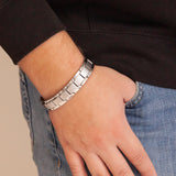 Man wearing the Brilliant Balance stainless steel bracelet with thumb in pocket, showing matte and polished contrast on angular links.