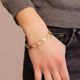 Woman wearing the Glistening Star gold titanium bracelet with thumb in pocket, showing X-shaped links and crystal accents.